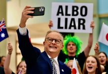 CANBERRA ON THE BRINK: Broken Vows and Tax Panic Ignite Demands for Constitutional Intervention PM Anthony Albanese with a person green hair holding a sign Albo Liar